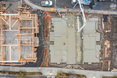 Çerçeveli, betonlu ve inşaat alanında çalışan koruyucu giysili işçilerin bulunduğu bir inşaat alanının yukarıdan aşağıya bakan görüntüsü.. 