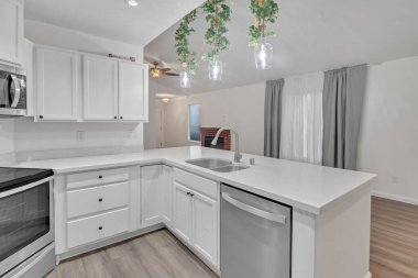 Brentwood, California 'da. 17 Aralık 2024 - Banliyödeki bir evde paslanmaz çelik aletler, kolye ışıkları ve beyaz tezgahlı beyaz bir mutfak