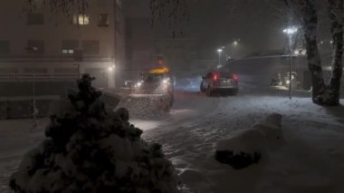 21 Kasım 2024 'te güçlü bir kar fırtınası Buochs, Nidwalden, İsviçre' yi kapladı. Bir kar küreme aracı gecenin geç saatlerine kadar çalışır. Şiddetli kar yağışı ve kış gökyüzü altında şehir sokaklarını temizler..