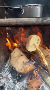 Sıcak bir orman anı. Çubukta kızartılmış ekmek ve kamp ateşinde demlenmiş çay. Basit açık hava yemekleri ve doğa cazibesi..