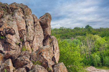 Yoğun bir orman üzerinde çarpıcı bir dokusu ve eşsiz rahatlama kuleleri olan dramatik kayalık bir uçurum. Doğal kaya oluşumu yemyeşil alana karşı duruyor ve nefes kesici bir manzara yaratıyor..