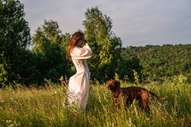 Güzel kırsal alanda köpeğiyle oynayan neşeli genç bir kadın. Kadın ve sırtında köpek yürüyor ve eğleniyor.