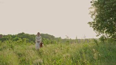 Güzel kırsal alanda köpeğiyle oynayan neşeli genç bir kadın. Kadın ve sırtında köpek yürüyor ve eğleniyor.