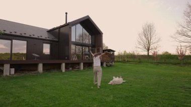 Günbatımında kırsalda yeni biçilmiş bir çimenlikte Sibirya köpeğiyle oynayan bir kadın.