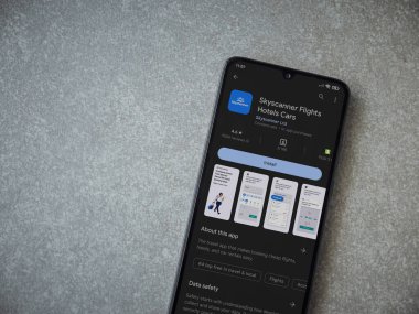 Lod, Israel - July 16,2023: Skyscanner app play store page on smartphone on ceramic stone background. Top view flat lay with copy space.