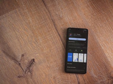 Lod, Israel - July 16,2023: Pango app play store page on smartphone on wooden background. Top view flat lay with copy space.
