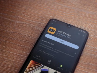 Lod, Israel - July 16,2023: USB Camera app play store page on smartphone on wooden background. Top view flat lay with copy space.
