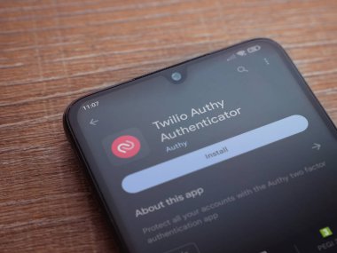 Lod, Israel - July 16,2023: Twilio Authy Authenticator app play store page on smartphone on wooden background. Top view flat lay with copy space.