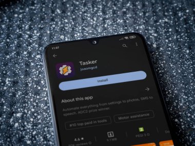 Lod, Israel - July 16,2023: Tasker app play store page on smartphone on a metallic background. Close up top view flat lay.