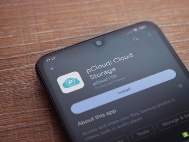 Lod, Israel - July 16,2023: pCloud app play store page on smartphone on wooden background. Top view flat lay with copy space.