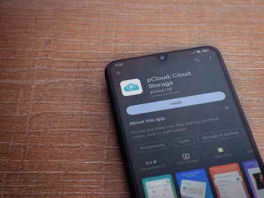 Lod, Israel - July 16,2023: pCloud app play store page on smartphone on wooden background. Top view flat lay with copy space.