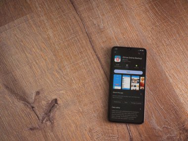 Lod, Israel - July 16,2023: IDrive Online Backup app play store page on smartphone on wooden background. Top view flat lay with copy space.