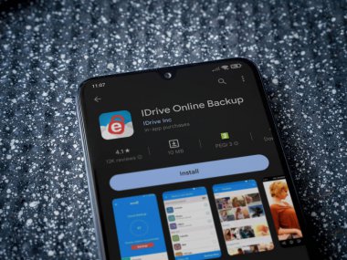 Lod, Israel - July 16,2023: IDrive Online Backup app play store page on smartphone on a metallic background. Close up top view flat lay.