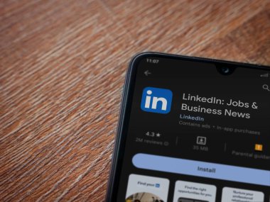 Lod, Israel - July 16,2023: LinkedIn app play store page on smartphone on wooden background. Top view flat lay with copy space.