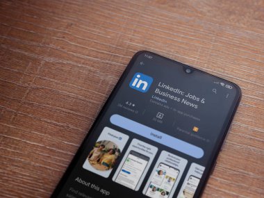 Lod, Israel - July 16,2023: LinkedIn app play store page on smartphone on wooden background. Top view flat lay with copy space.