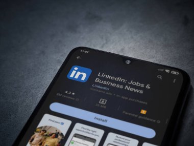 Lod, Israel - July 16,2023: LinkedIn app play store page on smartphone on a dark marble stone background. Top view flat lay with copy space.