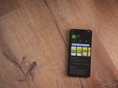 Lod, Israel - July 16,2023: iHerb app play store page on smartphone on wooden background. Top view flat lay with copy space.