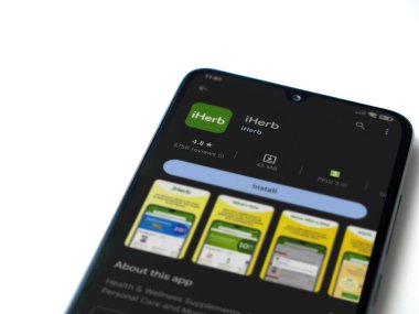 Lod, Israel - July 16,2023: iHerb app play store page on smartphone on white background. Top view flat lay with copy space.