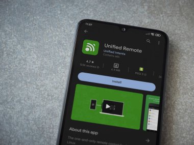 Lod, Israel - July 16,2023: Unified Remote app play store page on smartphone on ceramic stone background. Top view flat lay with copy space.