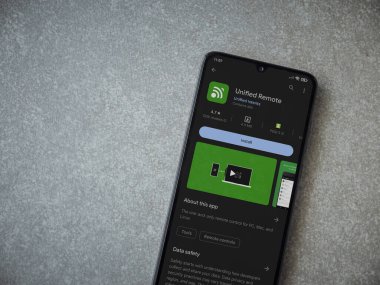 Lod, Israel - July 16,2023: Unified Remote app play store page on smartphone on ceramic stone background. Top view flat lay with copy space.