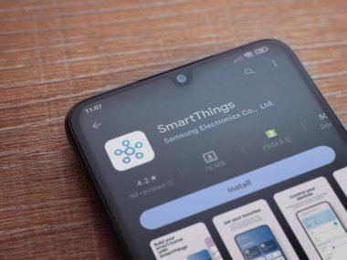 Lod, Israel - July 16,2023: Smartthings app play store page on smartphone on wooden background. Top view flat lay with copy space.