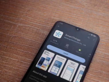 Lod, Israel - July 16,2023: Smartthings app play store page on smartphone on wooden background. Top view flat lay with copy space.
