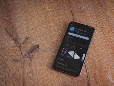 Lod, Israel - July 16,2023: Smart Life app play store page on smartphone on wooden background. Top view flat lay with copy space.