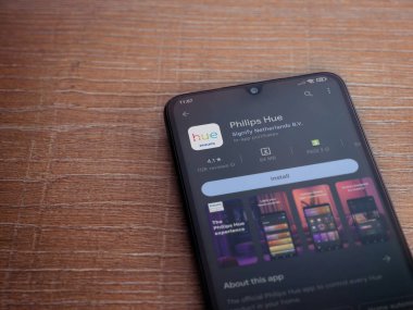Lod, Israel - July 16,2023: Philips Hue app play store page on smartphone on wooden background. Top view flat lay with copy space.