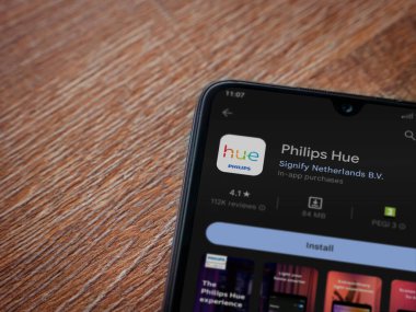 Lod, Israel - July 16,2023: Philips Hue app play store page on smartphone on wooden background. Top view flat lay with copy space.
