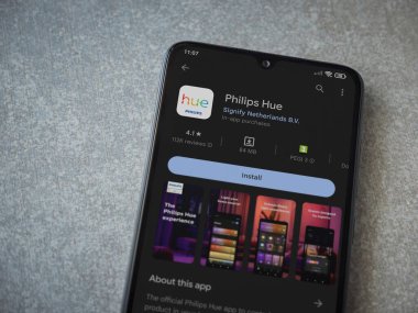 Lod, Israel - July 16,2023: Philips Hue app play store page on smartphone on ceramic stone background. Top view flat lay with copy space.