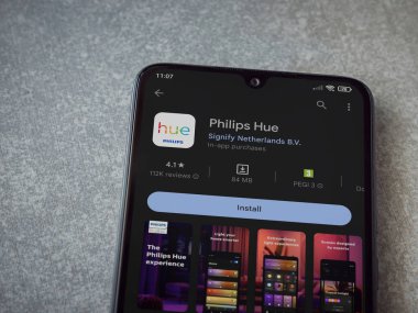 Lod, Israel - July 16,2023: Philips Hue app play store page on smartphone on ceramic stone background. Top view flat lay with copy space.