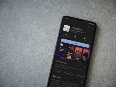 Lod, Israel - July 16,2023: Philips Hue app play store page on smartphone on ceramic stone background. Top view flat lay with copy space.