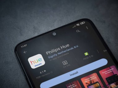 Lod, Israel - July 16,2023: Philips Hue app play store page on smartphone on a dark marble stone background. Top view flat lay with copy space.