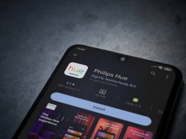 Lod, Israel - July 16,2023: Philips Hue app play store page on smartphone on a dark marble stone background. Top view flat lay with copy space.