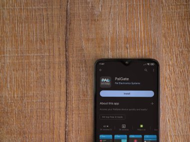 Lod, Israel - July 16,2023: PalGate app play store page on smartphone on wooden background. Top view flat lay with copy space.