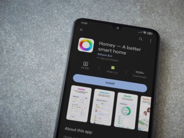 Lod, Israel - July 16,2023: Homey app play store page on smartphone on ceramic stone background. Top view flat lay with copy space.