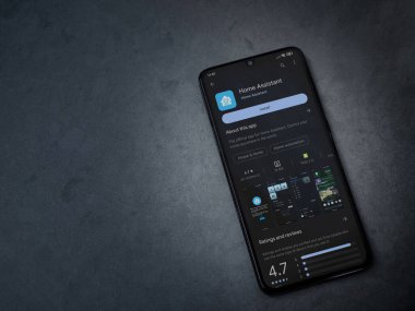 Lod, Israel - July 16,2023: Home Assistant app play store page on smartphone on a dark marble stone background. Top view flat lay with copy space.