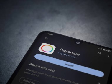 Lod, Israel - July 16,2023: Payoneer app play store page on smartphone on a dark marble stone background. Top view flat lay with copy space.
