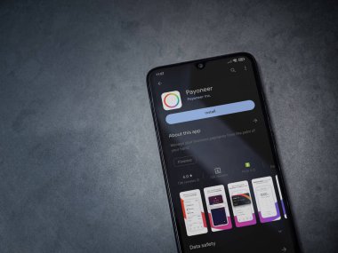 Lod, Israel - July 16,2023: Payoneer app play store page on smartphone on a dark marble stone background. Top view flat lay with copy space.