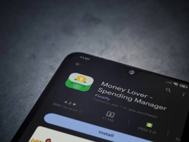 Lod, Israel - July 16,2023: Money Lover app play store page on smartphone on a dark marble stone background. Top view flat lay with copy space.