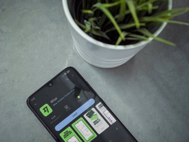 Lod, Israel - July 16,2023: Modern workspace with smartphone with Wise app play store page on marble background. Close up top view flat lay.