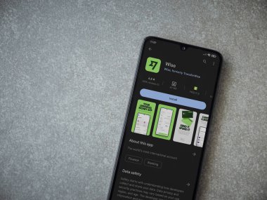 Lod, Israel - July 16,2023: Wise app play store page on smartphone on ceramic stone background. Top view flat lay with copy space.