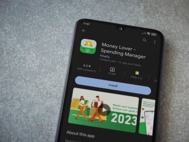 Lod, Israel - July 16,2023: Money Lover app play store page on smartphone on ceramic stone background. Top view flat lay with copy space.