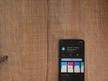 Lod, Israel - July 16,2023: Spender app play store page on smartphone on wooden background. Top view flat lay with copy space.
