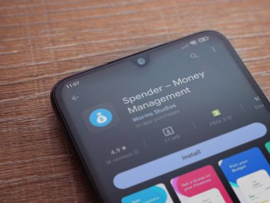 Lod, Israel - July 16,2023: Spender app play store page on smartphone on wooden background. Top view flat lay with copy space.