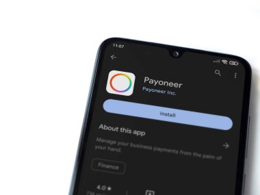 Lod, Israel - July 16,2023: Payoneer app play store page on smartphone on white background. Top view flat lay with copy space.