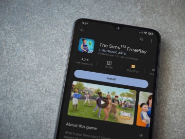 Lod, Israel - July 16,2023: The Sims FreePlay app play store page on smartphone on ceramic stone background. Top view flat lay with copy space.