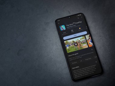 Lod, Israel - July 16,2023: The Sims FreePlay app play store page on smartphone on a dark marble stone background. Top view flat lay with copy space.