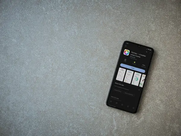 Lod, Israel - July 16,2023: Homey app play store page on smartphone on ceramic stone background. Top view flat lay with copy space.