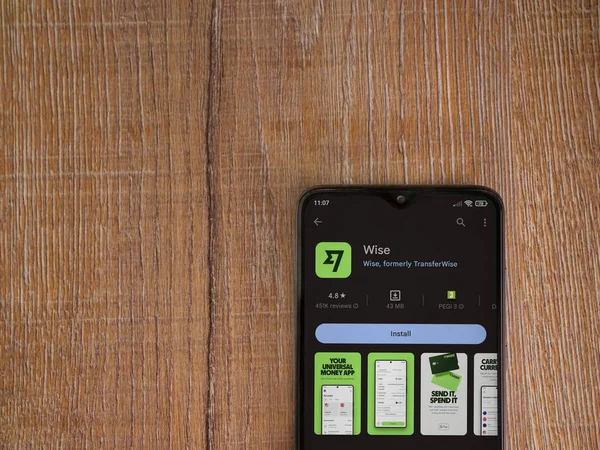 Lod, Israel - July 16,2023: Wise app play store page on smartphone on wooden background. Top view flat lay with copy space.